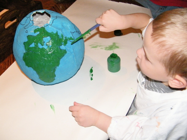 Painting on the continents of a DIY globe kids can make to study geology, geography and space.