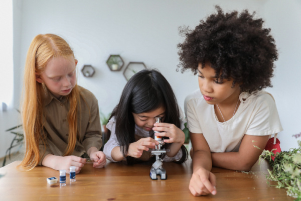 Kids looking at microscope exploring science. Getting kids interested in science can be done in some creative ways. this list is 5 ideas to try.