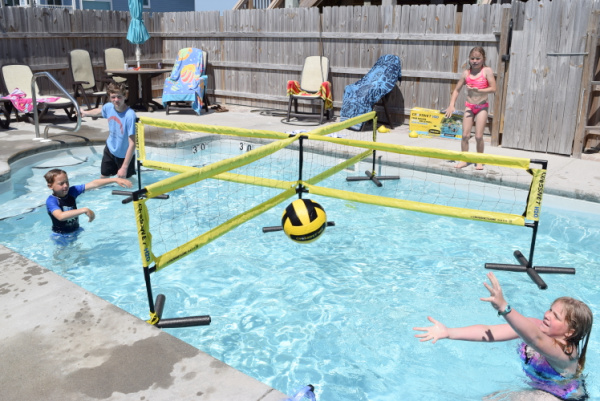 Anak-anak bermain dengan jaring Crossnet H2O di kolam renang untuk bermain di luar ruangan musim panas.