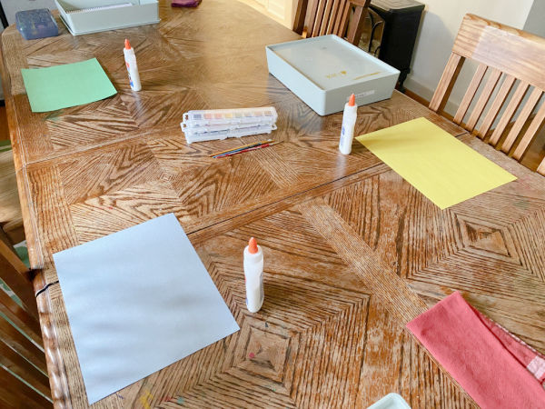 Meja disiapkan dengan persediaan untuk kegiatan melukis garam dan cat air Valentine.