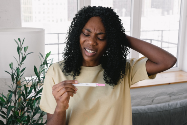 Woman reading pregnancy test with stressed look on her face. Title reads, when you can't get pregnant. The real story behind fertility challenges told in the new book The Good News Is You Don't Have Endometriosis.
