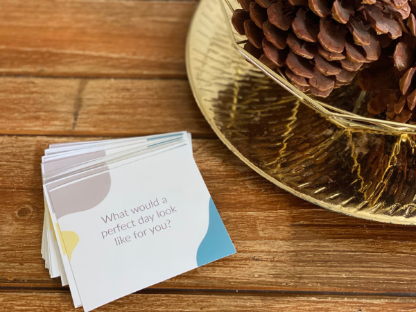 Pile of family conversation starter cards on coffee table next to a bowl of pinecones. 