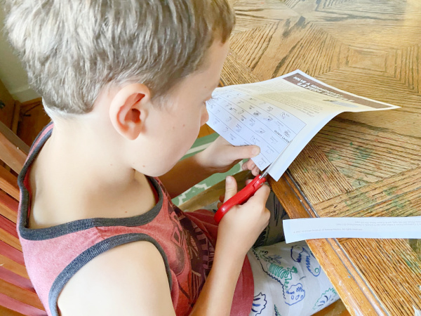 Child cutting the strips of paper from the geology timeline worksheet.