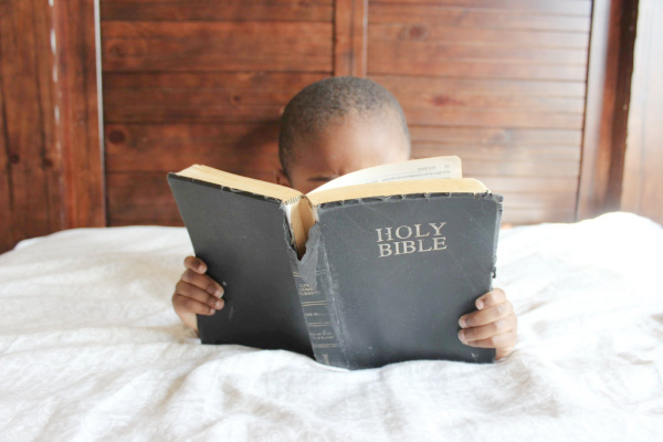 Child reading the Bible. Article details sharing the gospel with kids.