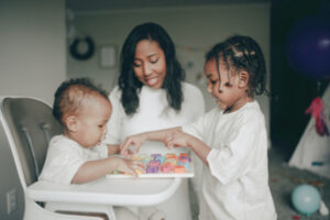 Mom and two kids playing with a puzzle together. Puzzles are one of the 10 multi-age activities in this list that encourage your kids curiosity.