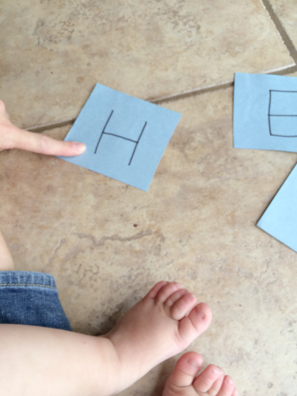 Pointing to the first letter card to emphasize visual and auditory connection.