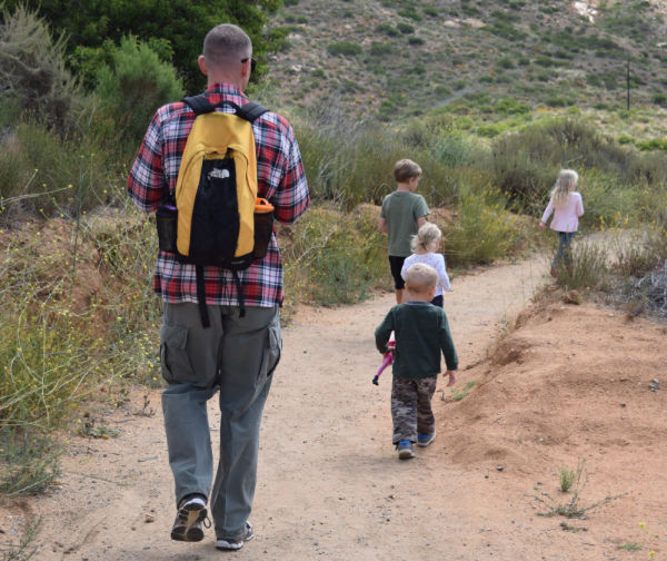 Children walking on a trail with dad. Article title is Mom's Guide to a Successful Summer with kids.