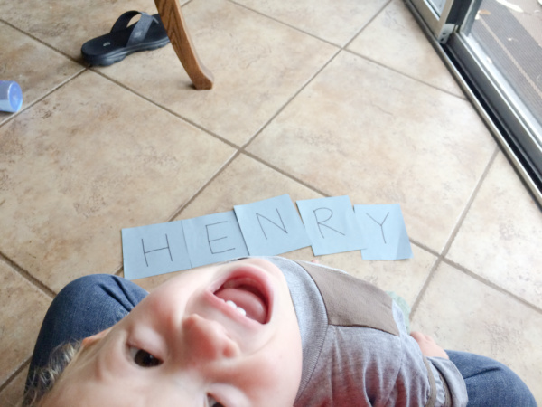 Toddler boy with cards that spell out his name.