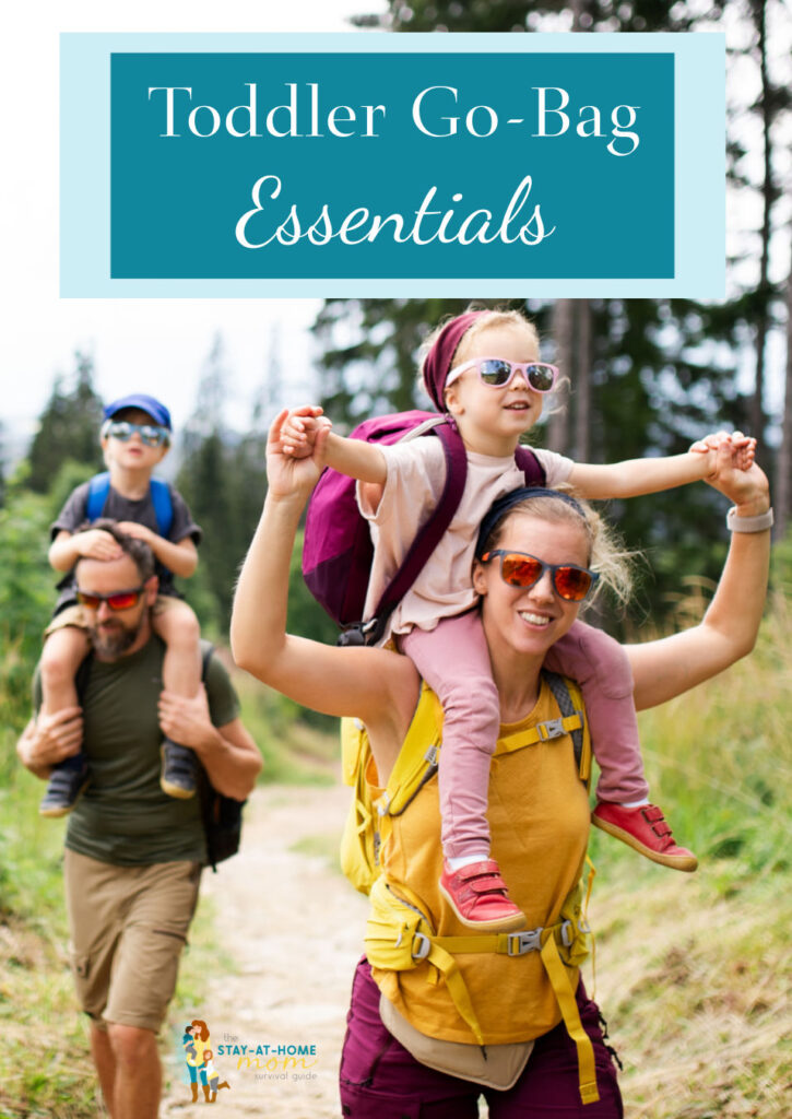 Family hiking with mom and dad carrying kids on their shoulders text reads toddler go-bag essentials.