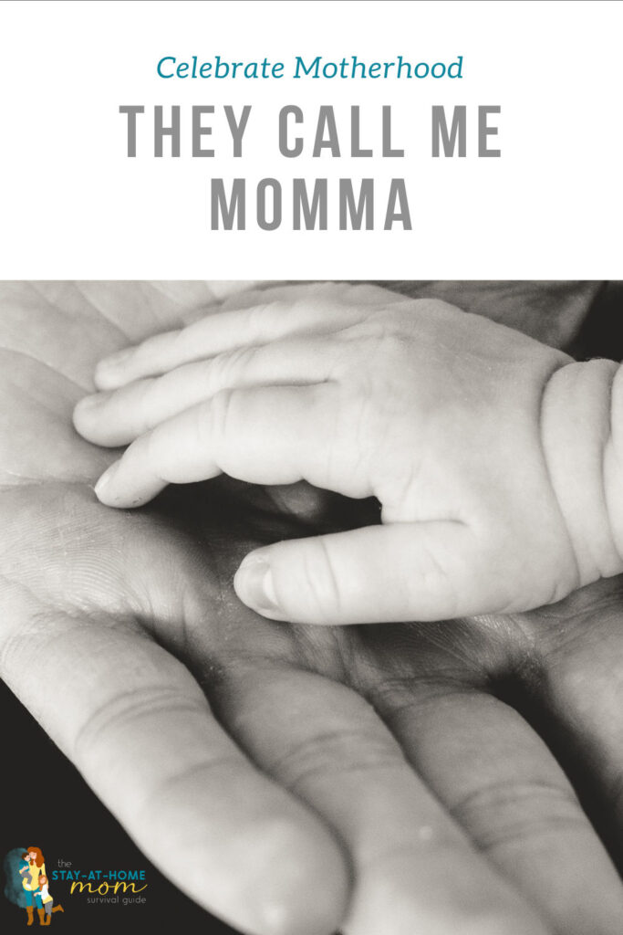 Black and white photo of an adult hand and a baby hand. Text reads celebrate motherhood they call me momma. 